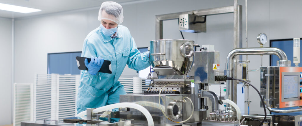 Funcionária da área de alimentos com um tablet na mão, conferindo os parâmetros dos equipamentos grandes
