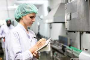 Profissional de qualidade registrando não conformidade em sistema digital na indústria de alimentos